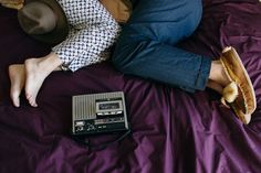 a man laying on top of a bed next to an old fashioned radio and hat