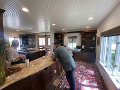 a man standing at the bar in a kitchen with two other men working behind him