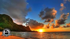 the sun is setting over an ocean with mountains in the background and people walking on the beach