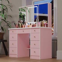 a pink vanity with lots of makeup on it in a room next to a potted plant