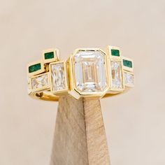 Product Details Ring Style: The Greta" is an art deco-style bezel set moissanite women's engagement ring with moissanite accent stones and a malachite stacking band. Many other center stone options are available upon request. Center Stone: 8x6mm Emerald Cut Moissanite Materials: 14K white gold engagement ring featuring 3 main moissanite stones, baguette moissanite side stones, and a malachite inlay tracer. Customizable: Because each ring is handcrafted to order, we can customize yours using unique materials, gemstones, or design features, often without any added cost! We can even use personal materials that you send! Basic customizations, such as material swaps, can be accommodated by simply adding a request in the “Custom Requests” section during checkout. For more extensive customization Unique Bezel Set Engagement Ring, Brand Identity Jewelry, Engagement Ring Stack, Non Traditional Wedding Ring, Emerald Cut Moissanite Engagement Ring, Emerald Wedding Band, Bezel Set Engagement Ring, Art Deco Wedding Band, Bezel Engagement Ring