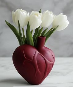 a heart shaped vase with white flowers in it