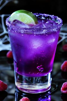 a purple drink with lime and raspberries on the table