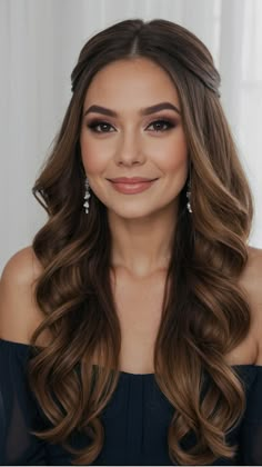 a woman with long brown hair wearing a black off the shoulder dress and diamond earrings