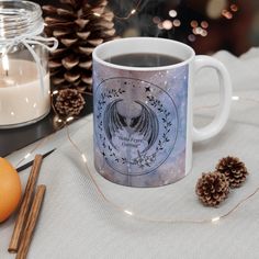 a coffee mug sitting on top of a table next to some pine cones and candles