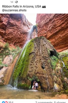 two people are standing in front of a waterfall with moss growing on the rocks and water running down it