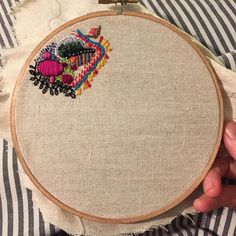 someone is holding up a small embroidery hoop