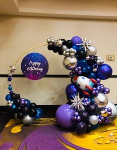 the balloon arch is decorated with purple, blue and silver balloons