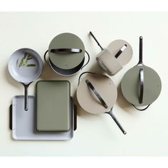 an assortment of kitchen utensils and pans on a white table top,