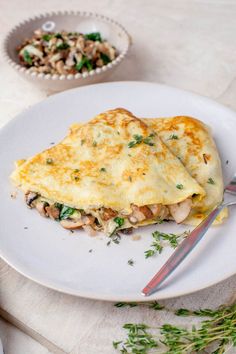 an omelet with mushrooms and herbs on a white plate