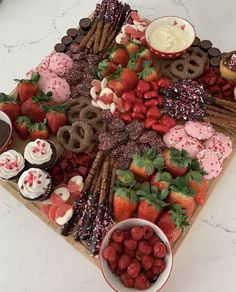 a platter with strawberries, pretzels, cookies and other desserts