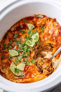 a white crock pot filled with mexican chicken enchilada casserole