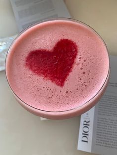 a pink drink with a heart on the top and a book in the back ground