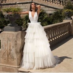 a woman in a white dress leaning against a stone wall