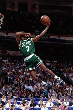 a basketball player jumping up into the air to dunk a ball in front of an audience