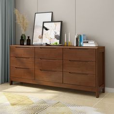 a wooden dresser with pictures and candles on it in a room next to a window