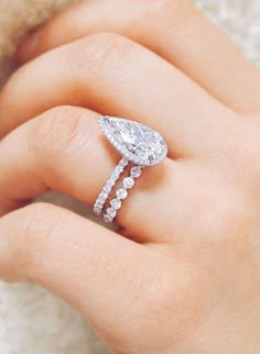 a woman's hand with a diamond ring on top of her finger and an engagement band