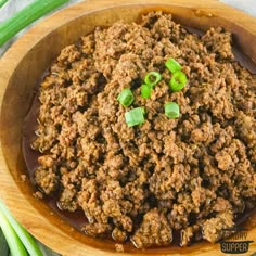 a wooden bowl filled with meat and green onions