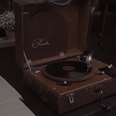 an old record player sitting on top of a suitcase