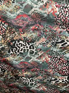 an animal print fabric with red, black and white designs on the top of it