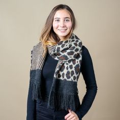 a woman wearing a leopard print scarf with fringes on her neck and black top