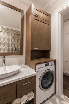 a washer and dryer in a bathroom with wood cabinets on either side of the sink