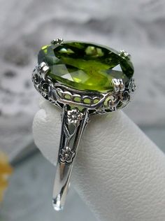 "Natural Green Peridot Sterling Silver Ring Edward Design#70z (smaller version) Custom Made Inspired by Edwardian jewelry of the early 1900s, I now offer this lovely Antique reproduction ring in sterling silver. This gorgeous ring is set with a stunning 4ct Natural Green Peridot gemstone. This genuine Peridot has good color and clarity (VS). The oval cut Peridot is 12mm (9/16th of an inch) Long by 10mm Wide (3/8th\"). The ring sits 6mm off the finger. The inside of the band s marked 925 for ster Elegant Peridot Jewelry With Prong Setting, Elegant Green Gemstones With Prong Setting, Classic Green Gemstone With Center Stone, Exquisite Green Rings With Diamond Cut, Exquisite Green Diamond Cut Rings, Elegant Peridot Ring Jewelry, Elegant Lime Green Ring For Gift, Elegant Lime Green Rings For Gift, Classic Peridot Green Rings