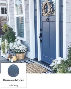 a blue front door with two potted plants on the side and a welcome mat