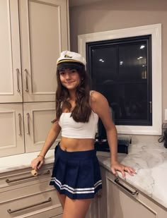 a young woman in a sailor outfit posing for a photo while standing on the kitchen counter