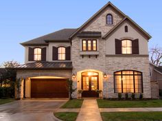 a large house with lots of windows and lights on it's front door at night