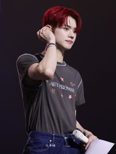 a young man with red hair and piercings holding a microphone in his right hand