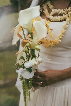 a bride holding a bouquet of flowers in her hands and wearing a necklace on her neck