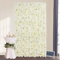 a white flower wall and table with a sign