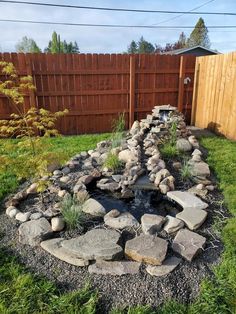 a garden with rocks and water in the center, along side a fenced area