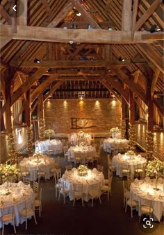 the inside of a barn with tables and chairs set up for a wedding reception in white linens