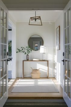 an entryway with a table, mirror and potted plant on the floor in front of it