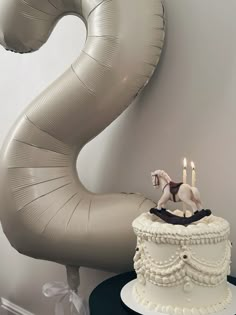 a birthday cake with two candles on top and a horse figurine next to it