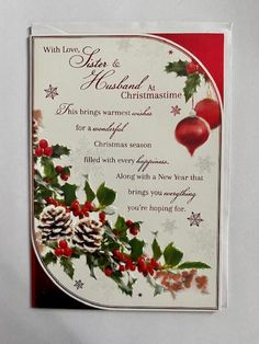 a christmas card with pine cones, holly and baubles on it's side