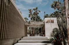 the entrance to an art museum with palm trees and flowers on the steps leading up to it