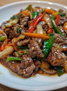 a white plate topped with meat and vegetables on top of a wooden table next to a fork