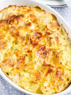 a casserole dish with potatoes and herbs in it on a blue tablecloth