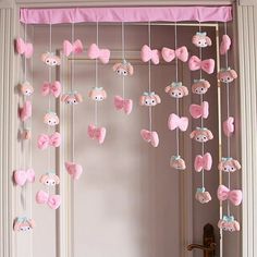 a pink and white baby mobile with teddy bears hanging from it's sides in front of a door