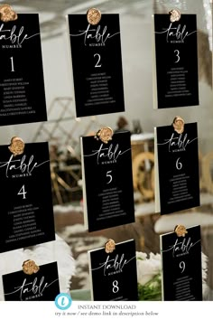 black and gold wedding seating cards on a glass table with white flowers in the center