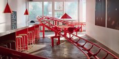 a long red bench sitting in the middle of a room next to a bar with stools