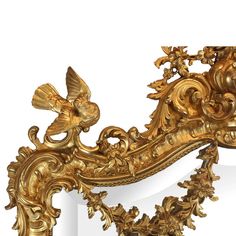 an ornate gold mirror frame with birds and flowers on the top, against a white background