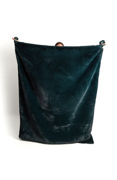 a dark green velvet bag with gold hardwares on the front and bottom, hanging from a metal hook