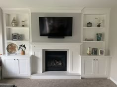 White custom built-in fireplace and television unit, with  open shelves and cabinetry. Electric Fireplace With Bookshelves On Each Side, Fireplace Set Back From Built Ins, Cupboards Around Fireplace, Fireplace With Bookshelves On Each Side Built In Shelves, Fireplace With Tv And Shelves, Cabinets On Both Sides Of Fireplace