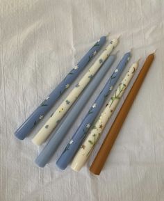 four blue and white candles sitting next to each other on top of a tablecloth