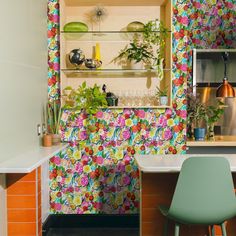 a kitchen with colorful floral wallpaper and green chairs in front of the counter top