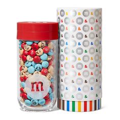 a jar filled with m and m candy next to a container full of m and m candies